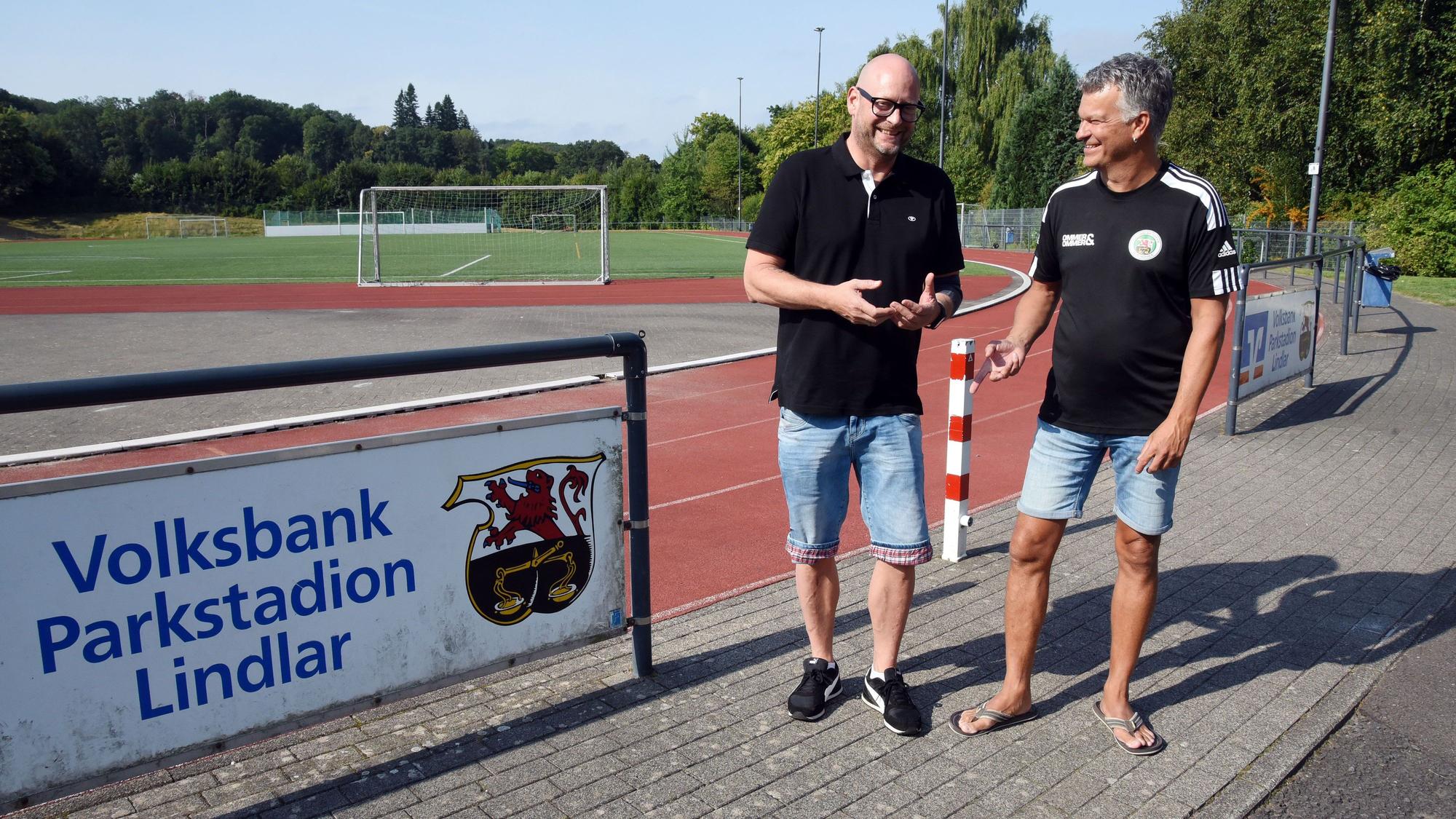Vorsitzender Andre Vicariesmann und Geschäftsführer Jörg Müller stehen an einem Sportplatz.