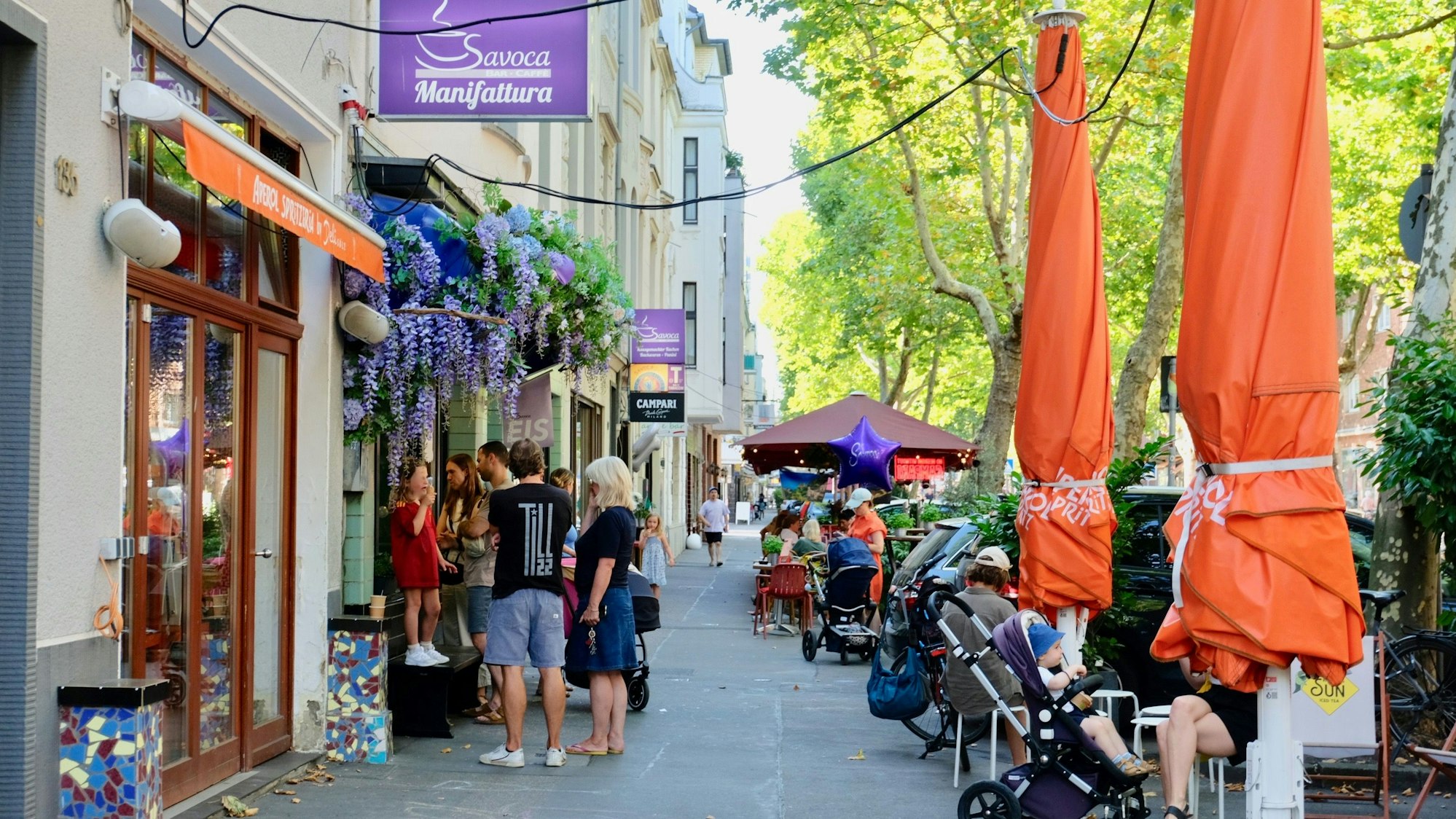 Am Fenster und im Außenbereich der Café-Bar Savoca auf dem Gottesweg sind viele Fans unterwegs.