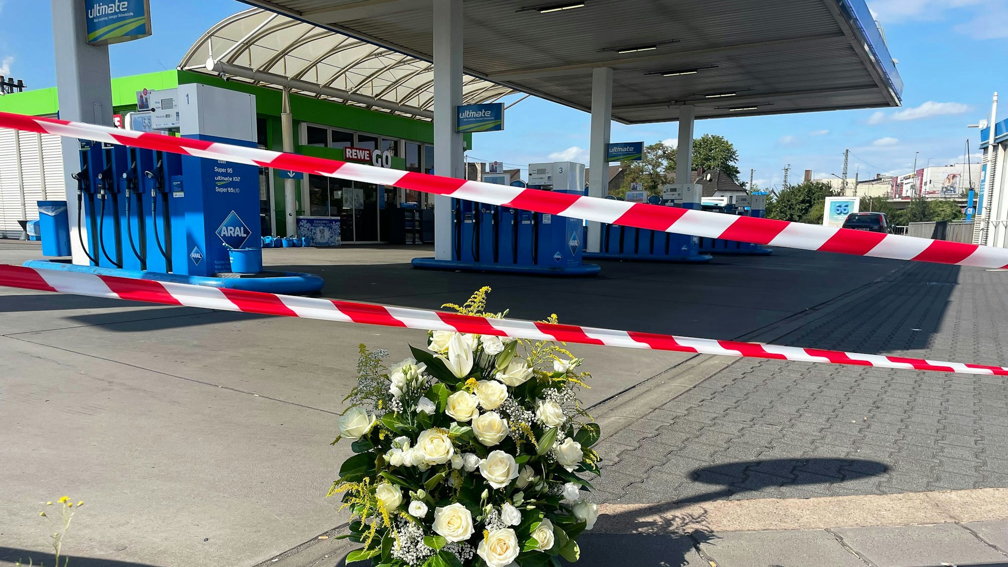 22.08.2025, Saarland, Völklingen: An der Tankstelle, an der nach einem Überfall ein Polizist getötet wurde, haben Mitarbeiter einen Kranz niedergelegt. Nach einem Raubüberfall auf die Tankstelle ist ein Polizist durch Schüsse getötet worden. Nach Angaben der Polizei hatte der mutmaßliche Täter dem Beamten bei einem Gerangel die Dienstwaffe entrissen und geschossen. Foto: Christian Schultz/dpa +++ dpa-Bildfunk +++