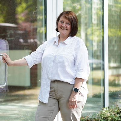 Das Foto zeigt eine Frau vor einer Halle.