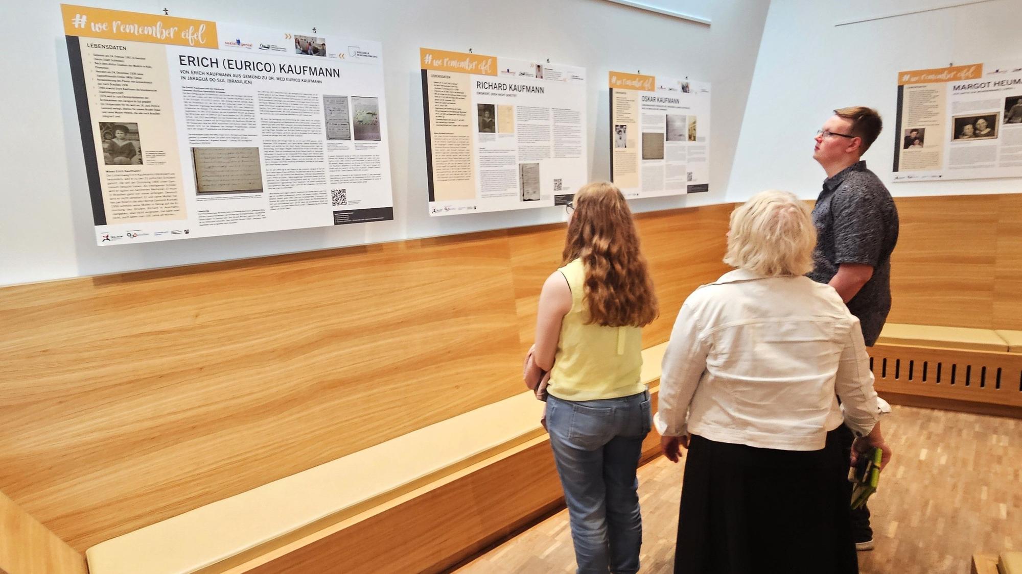 Das Foto zeigt Besucher der Ausstellung vor den Infotafeln mit den Lebensläufen.