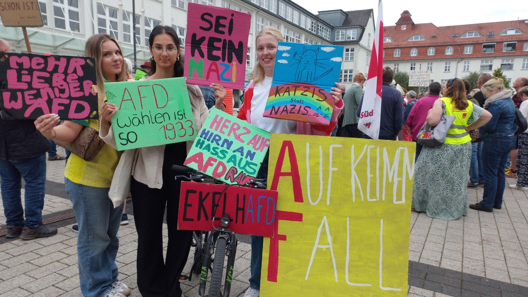 Zu sehen sind drei junge Frauen mit Plakaten.