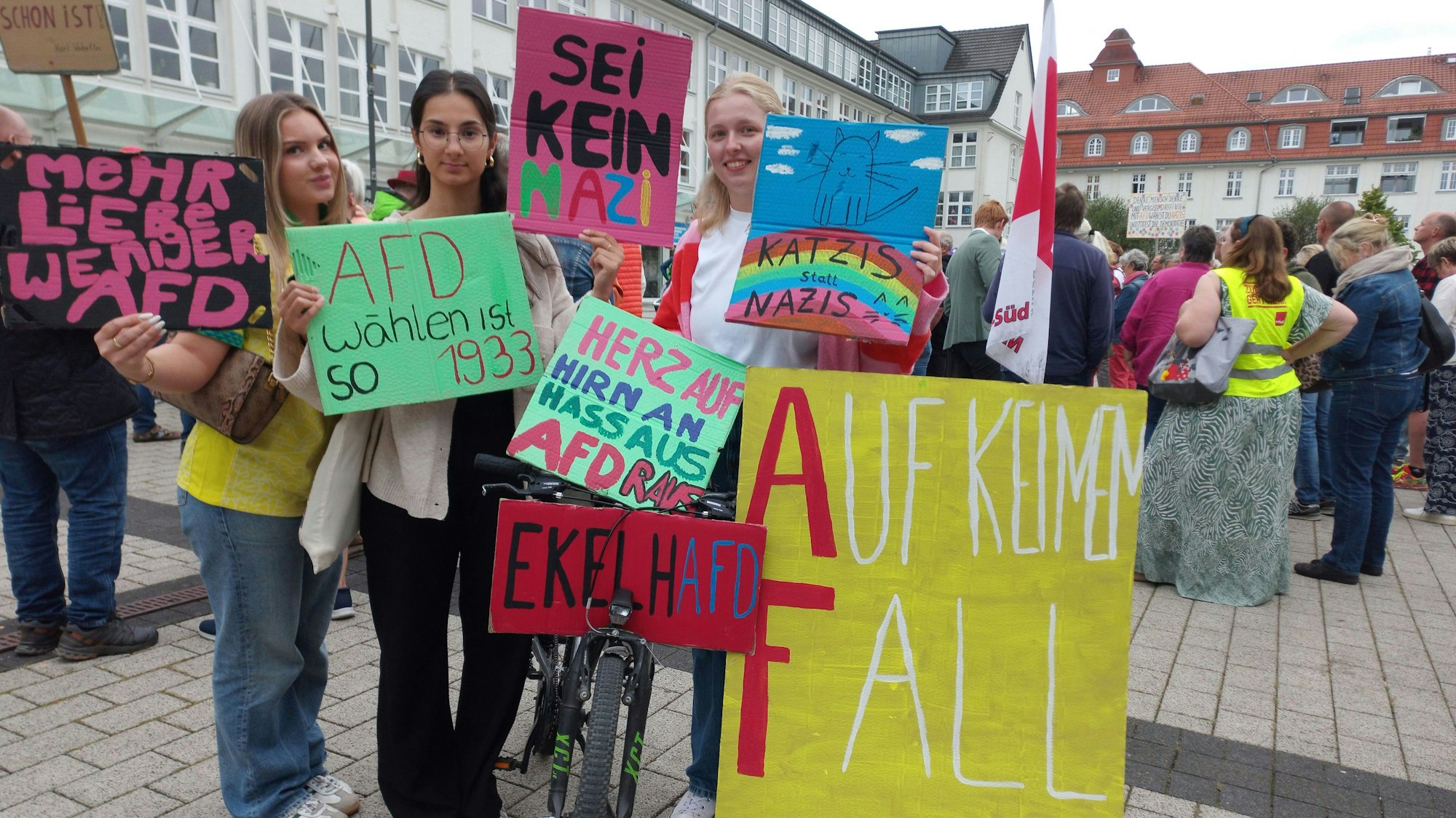 Zu sehen sind drei junge Frauen mit Plakaten.