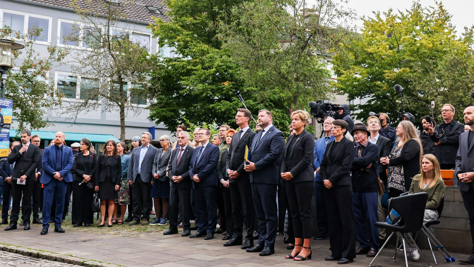 Politiker und Angehörige der Opfer stehen zusammen bei der Gedenkfeier ein Jahr nach dem Terroranschlag von Solingen.