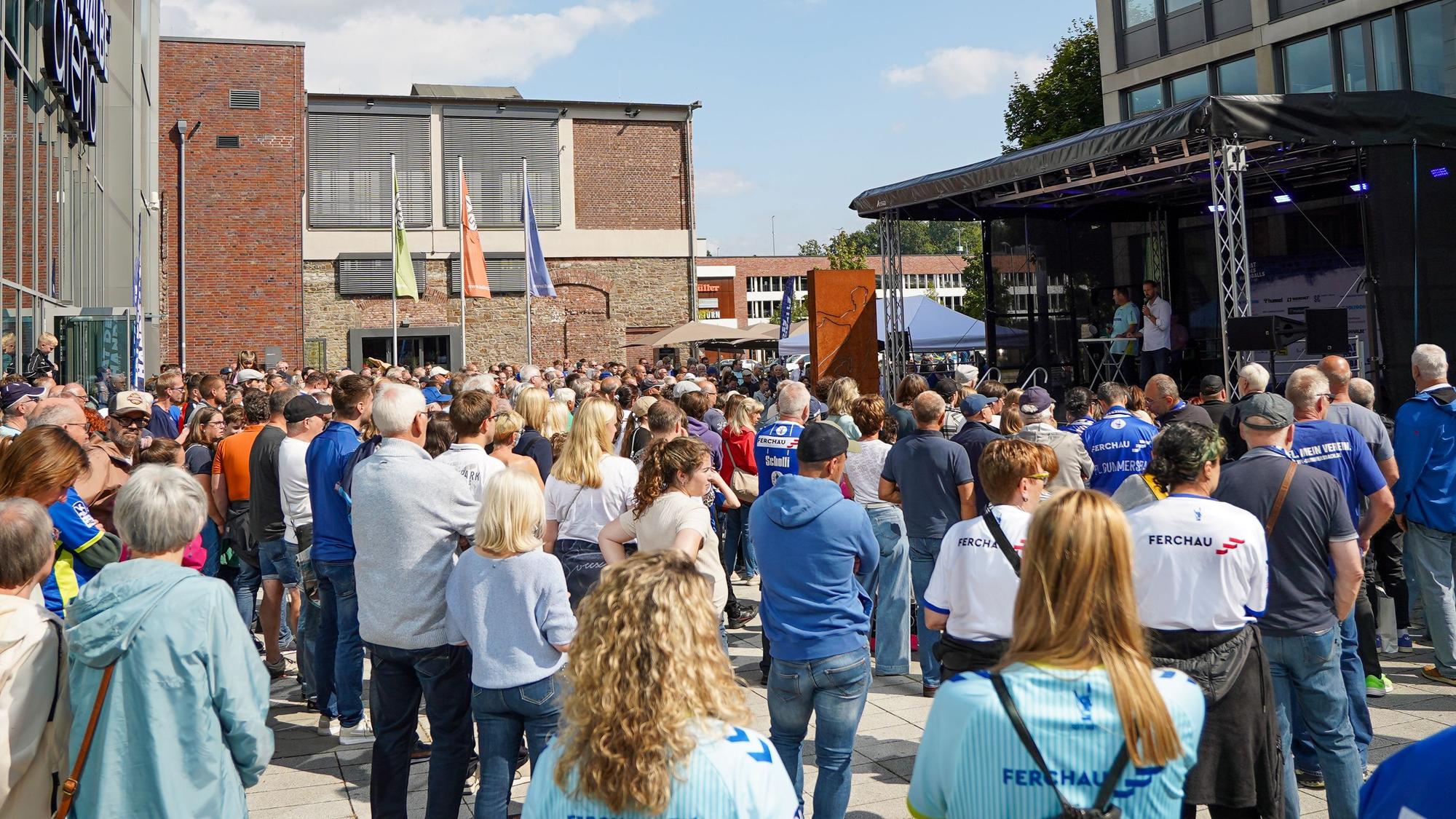 Viele Menschen in Trikots warten auf die Handballer.