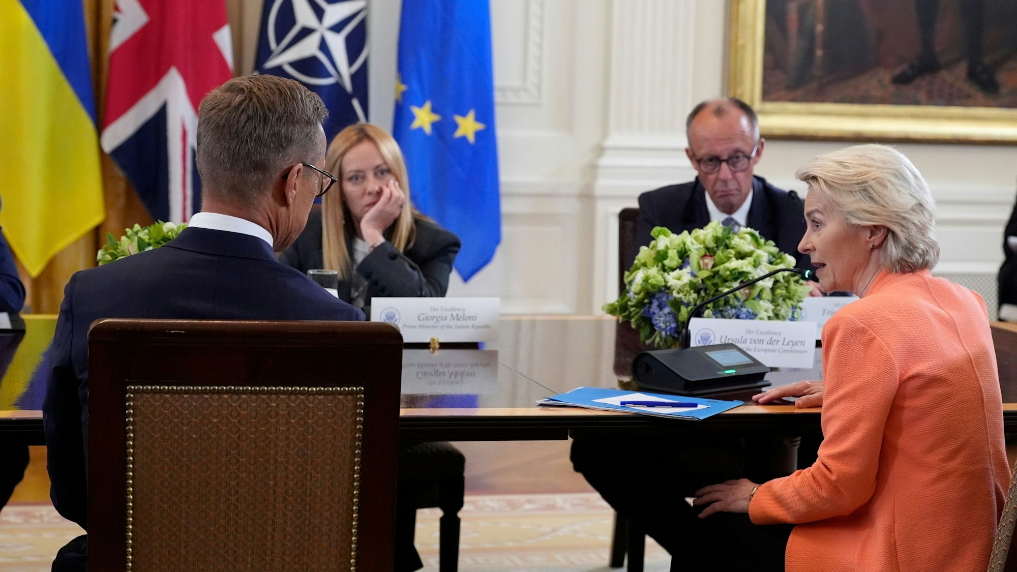 Die Präsidentin der Europäischen Kommission Ursula von der Leyen (r) spricht, während der finnische Präsident Alexander Stubb (l), Bundeskanzler Friedrich Merz (CDU) und die italienische Ministerpräsidentin Giorgia Meloni während eines Treffens mit US-Präsident Trump, dem ukrainischen Präsidenten Selenskyj und europäischen Staats- und Regierungschefs im Weißen Haus zuhören. (Archivbild)