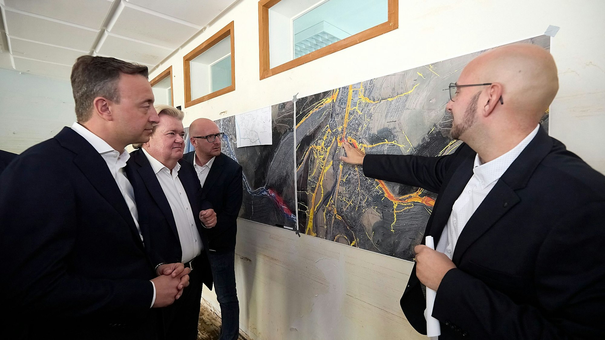 Paul Ziemiak, Klaus Voussem und Ingo Pfennings schauen auf luftbilder, die Frederik Link erläutert.