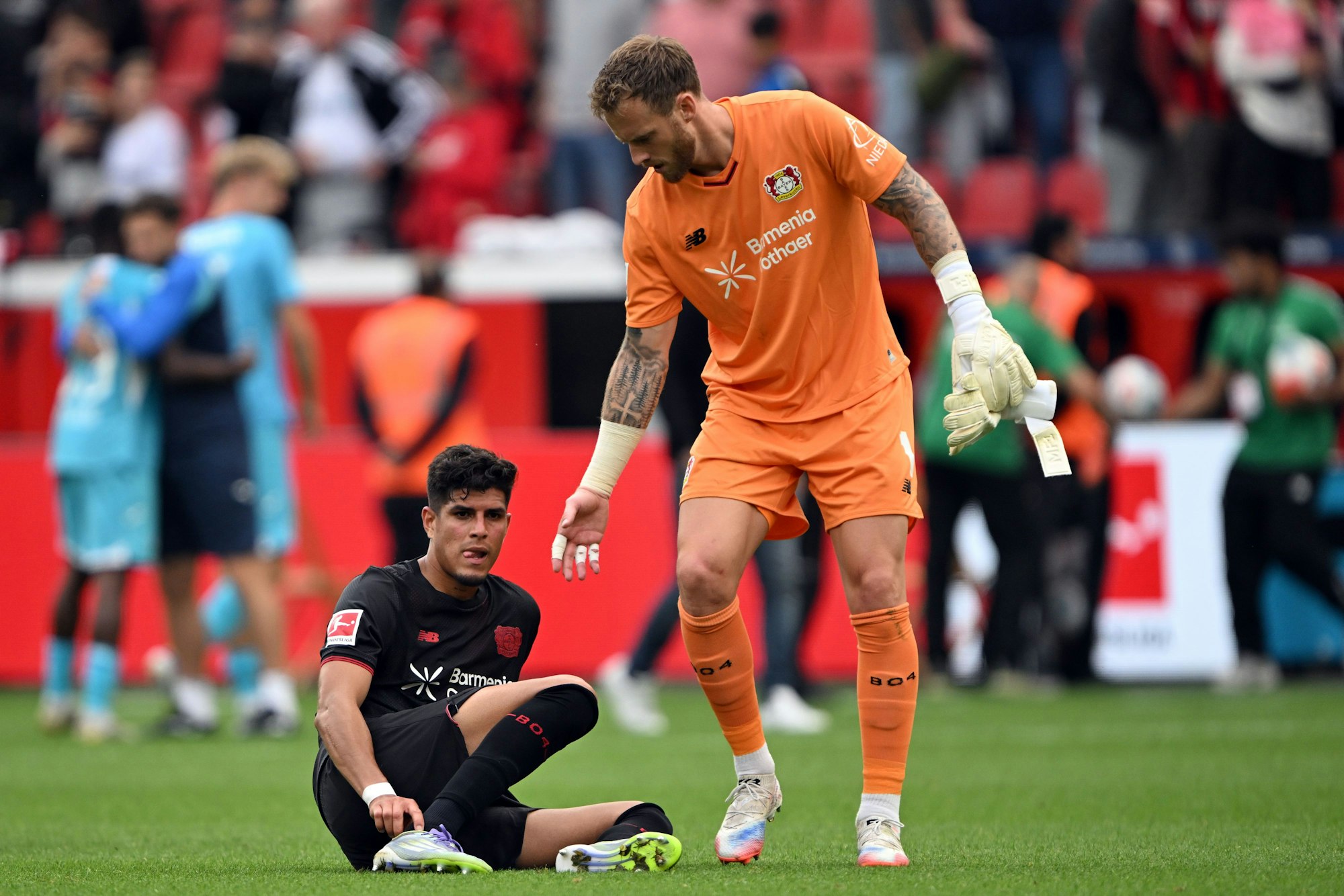 Leverkusener Aufbauhilfe: Torwart Mark Flekken reicht seinem Teamkollegen Piero Hincapié (l.) die Hand.