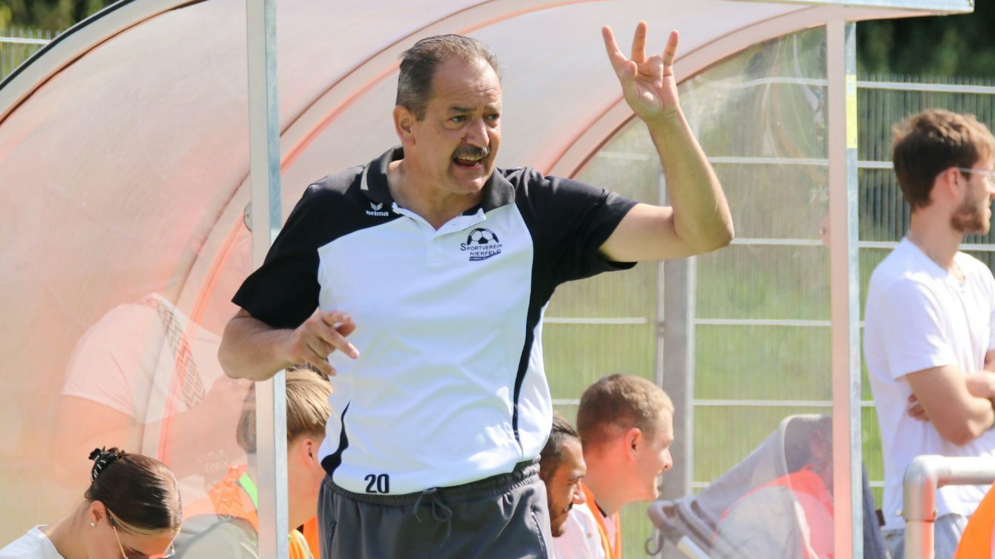 Dirk Scheer steht vor der Trainerbank und hält drei Finger hoch.