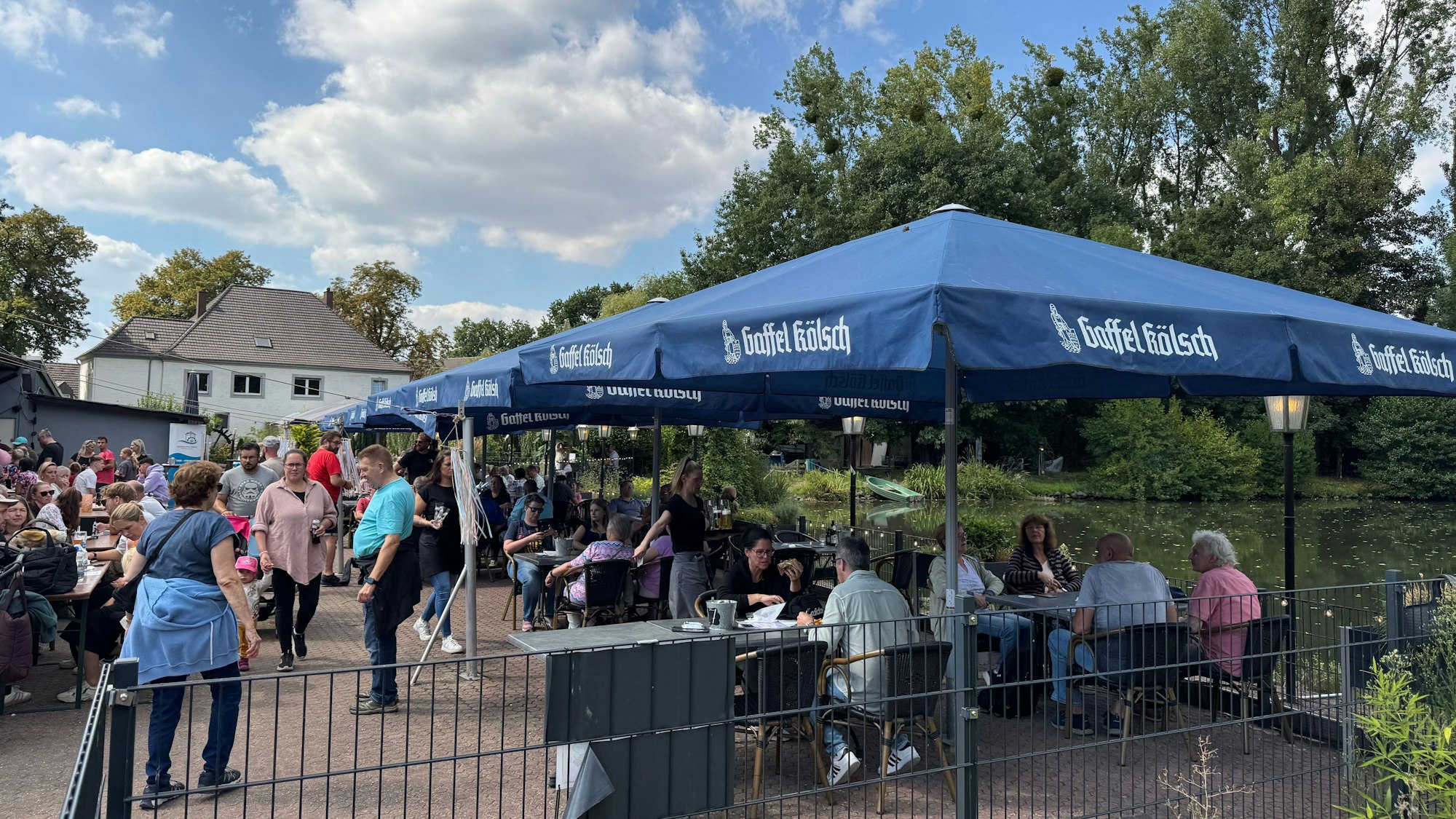 Auf dem Bild sind Menschen zu sehen, die in einem Biergarten sitzen.
