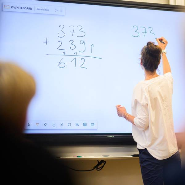 Eine Lehrerin schreibt eine Mathematikaufgabe auf eine digitale Schultafel (Symbolbild)