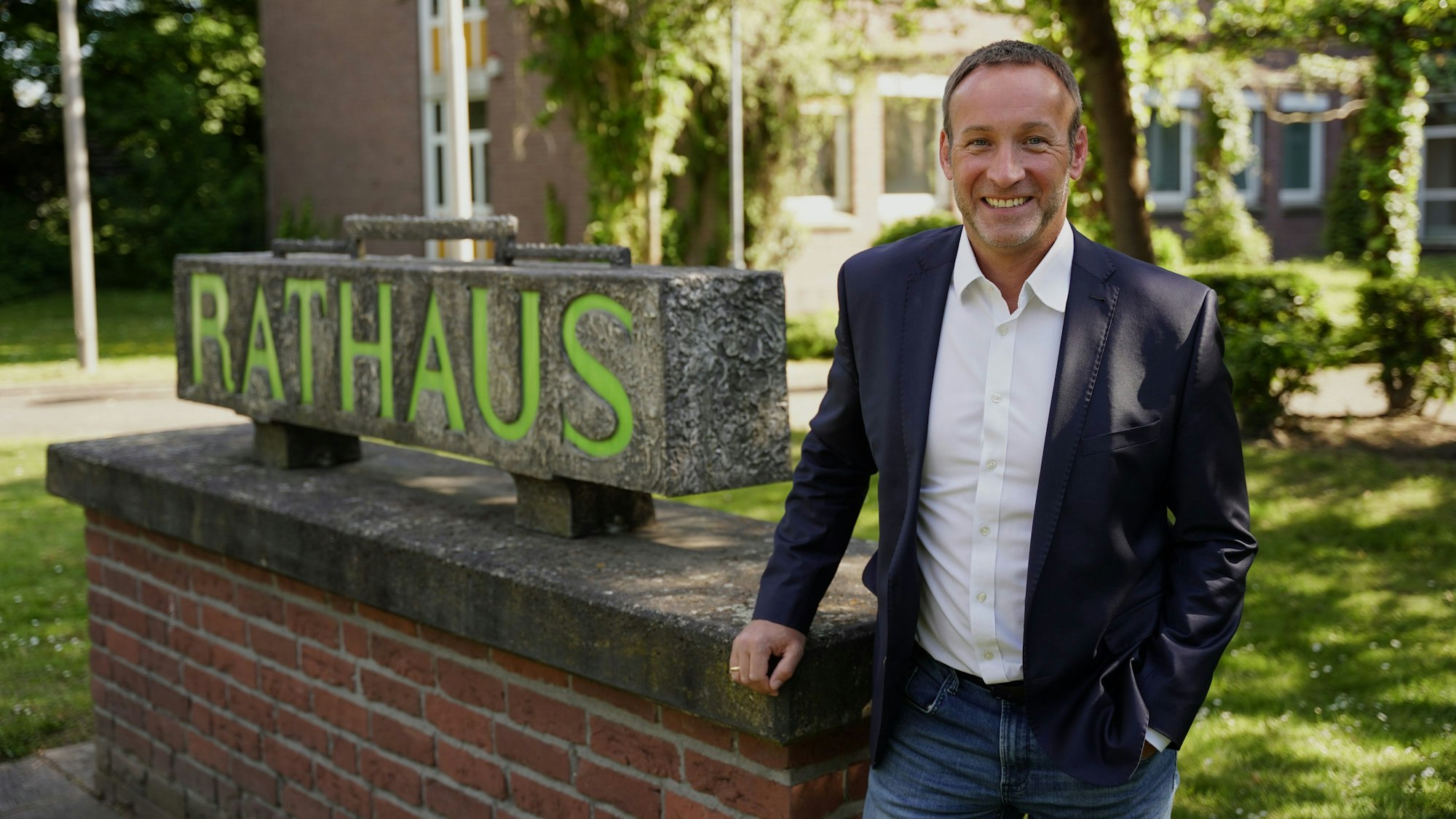 Ein Mann steht vor einem Rathaus.