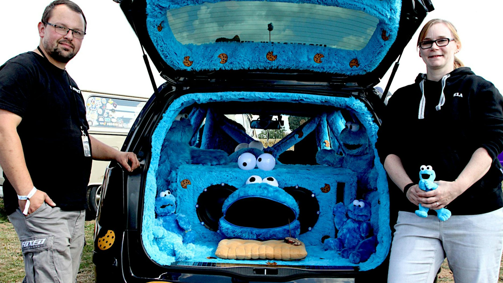 Michaela Ritter (l.) und Robert Majkowski stehen neben ihrem Opel. Im Kofferraum sitzt ein blaues Krümelmonster aus Plüsch.