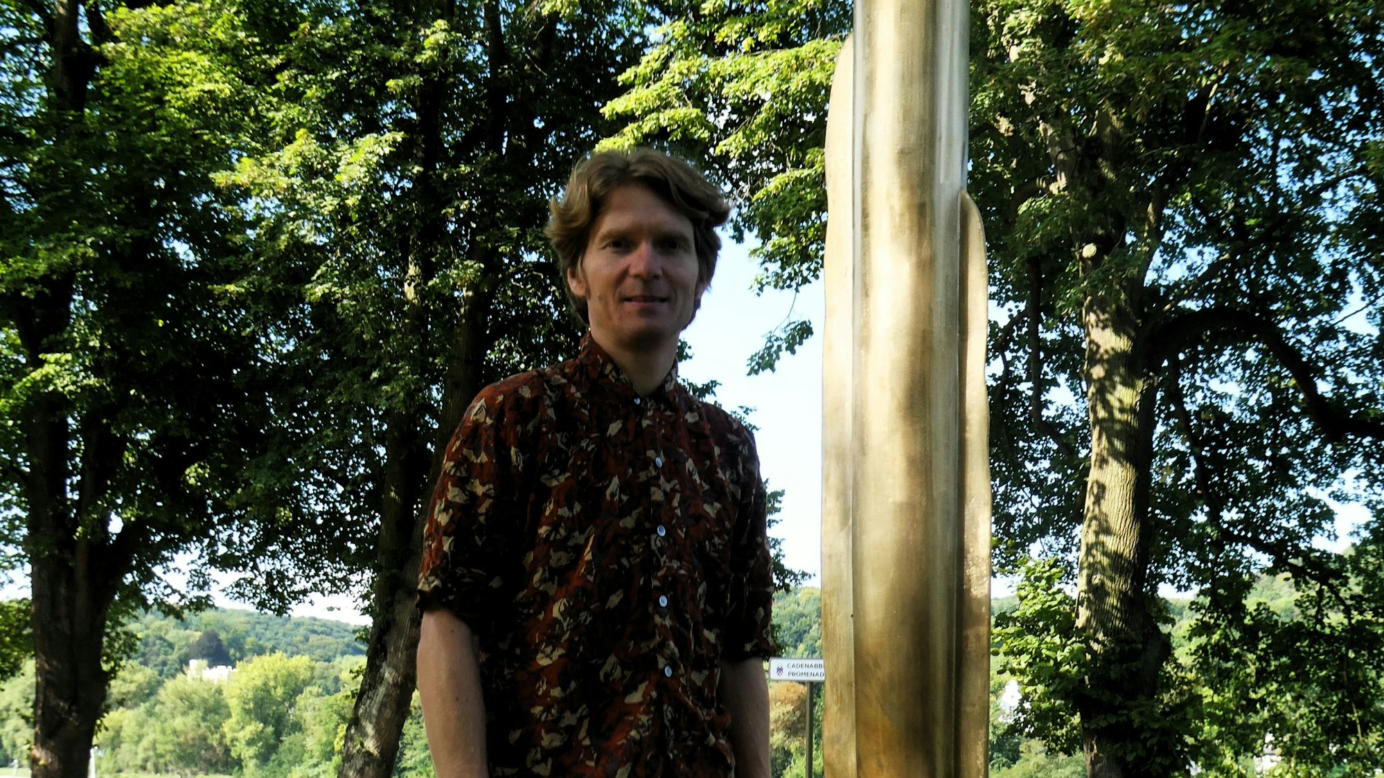 Ein junger Mann neben einer goldenen Skulptur.