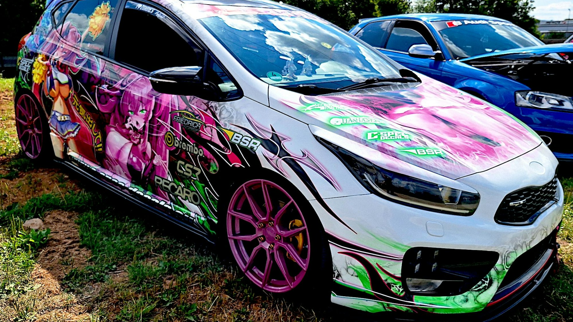 Das weiß lackierte Auto ist mit grellbunten Mangas beklebt.