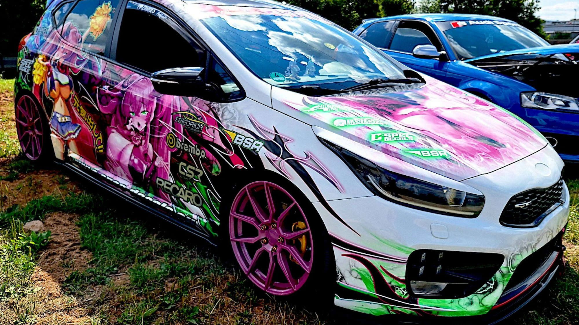 Das weiß lackierte Auto ist mit grellbunten Mangas beklebt.