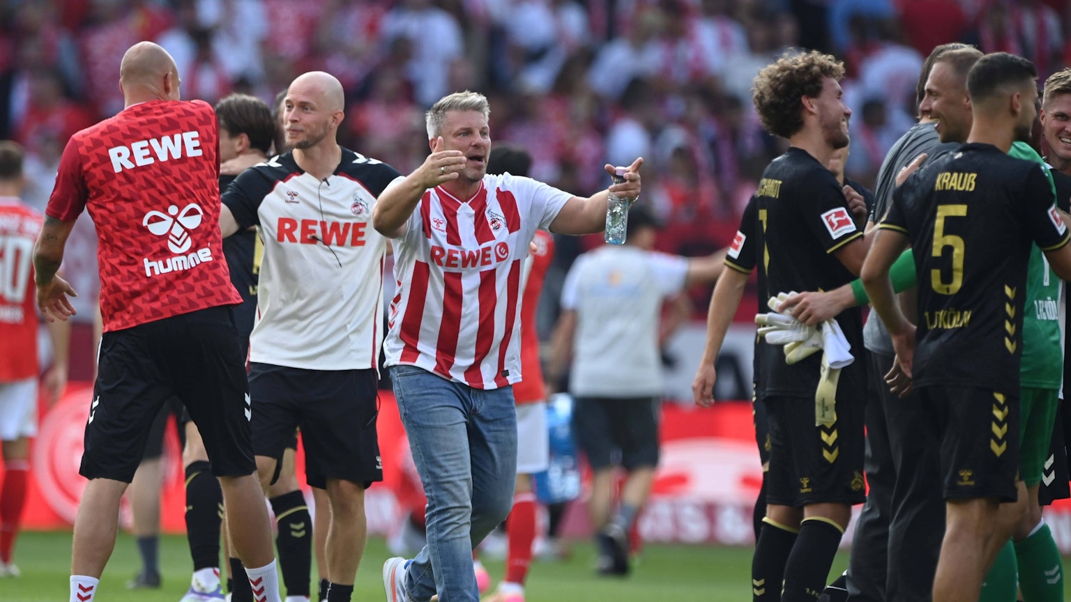 FC-Trainer Lukas Kwasniok läuft nach dem 1:0 in Mainz im Kölner Heimtrikot auf seine glücklichen Spieler zu.