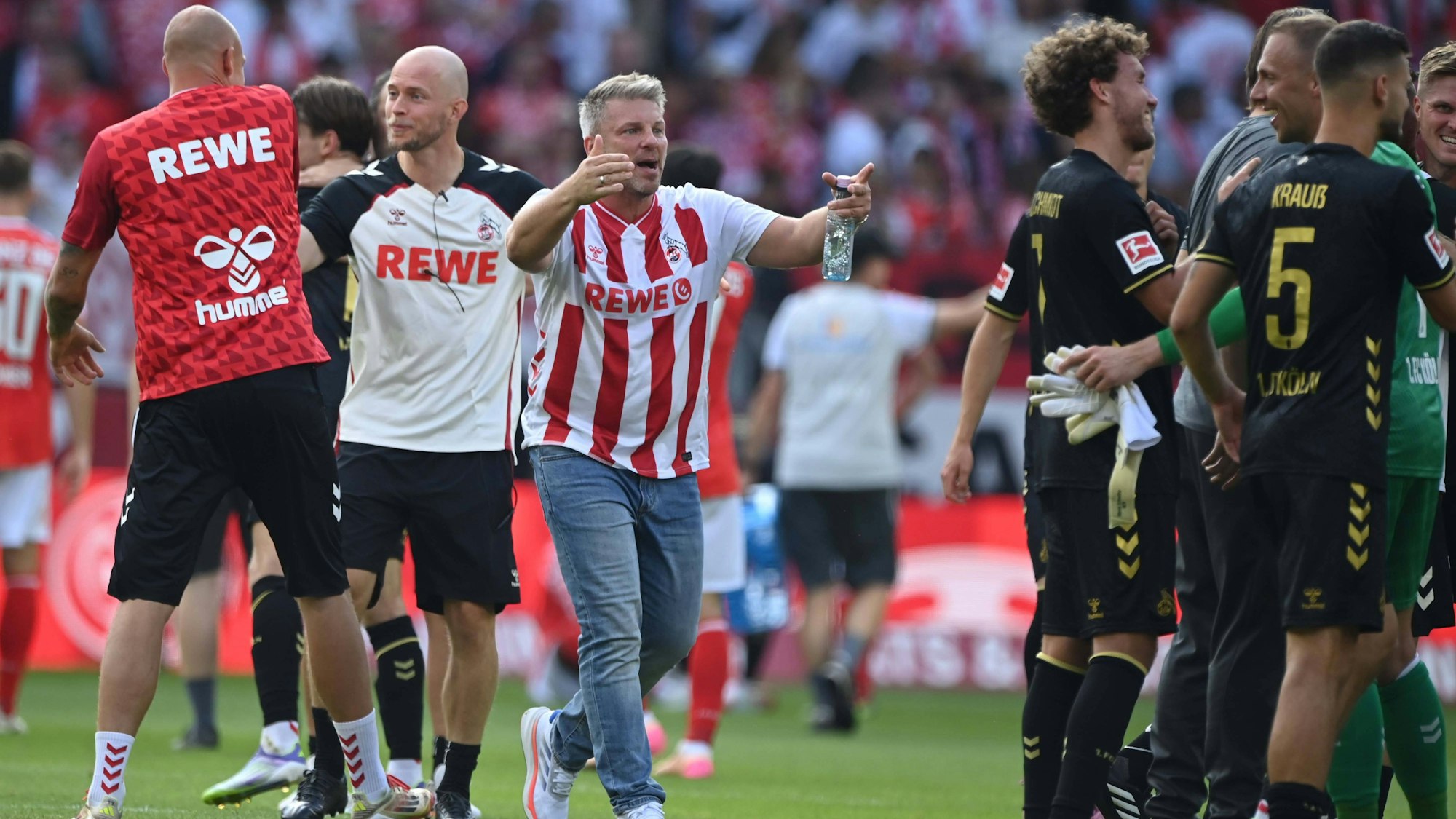 FC-Trainer Lukas Kwasniok läuft nach dem 1:0 in Mainz im Kölner Heimtrikot auf seine glücklichen Spieler zu.