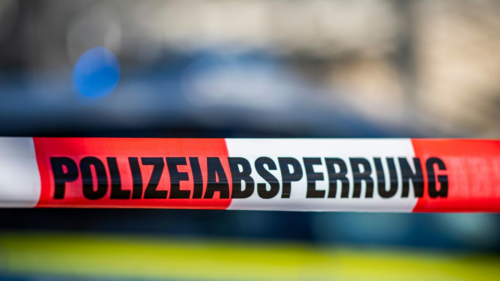 Ein Absperrband mit der Aufschrift «Polizeiabsperrung» ist vor einem Polizeiwagen aufgespannt.