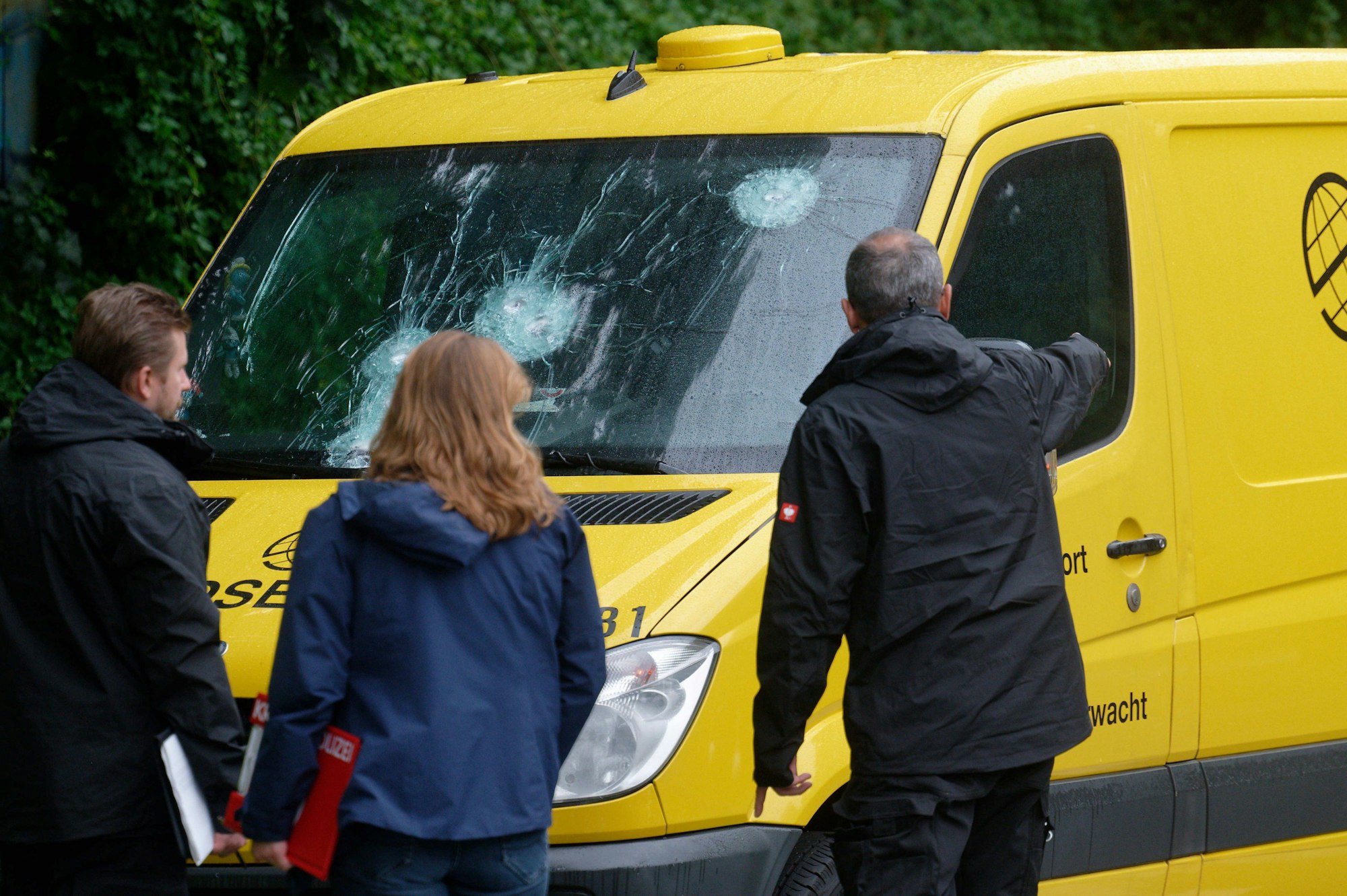 , Köln: Polizeibeamte stehen vor einem Geldtransporter, an dem Einschusslöcher auf der Windschutzscheibe zu sehen sind.