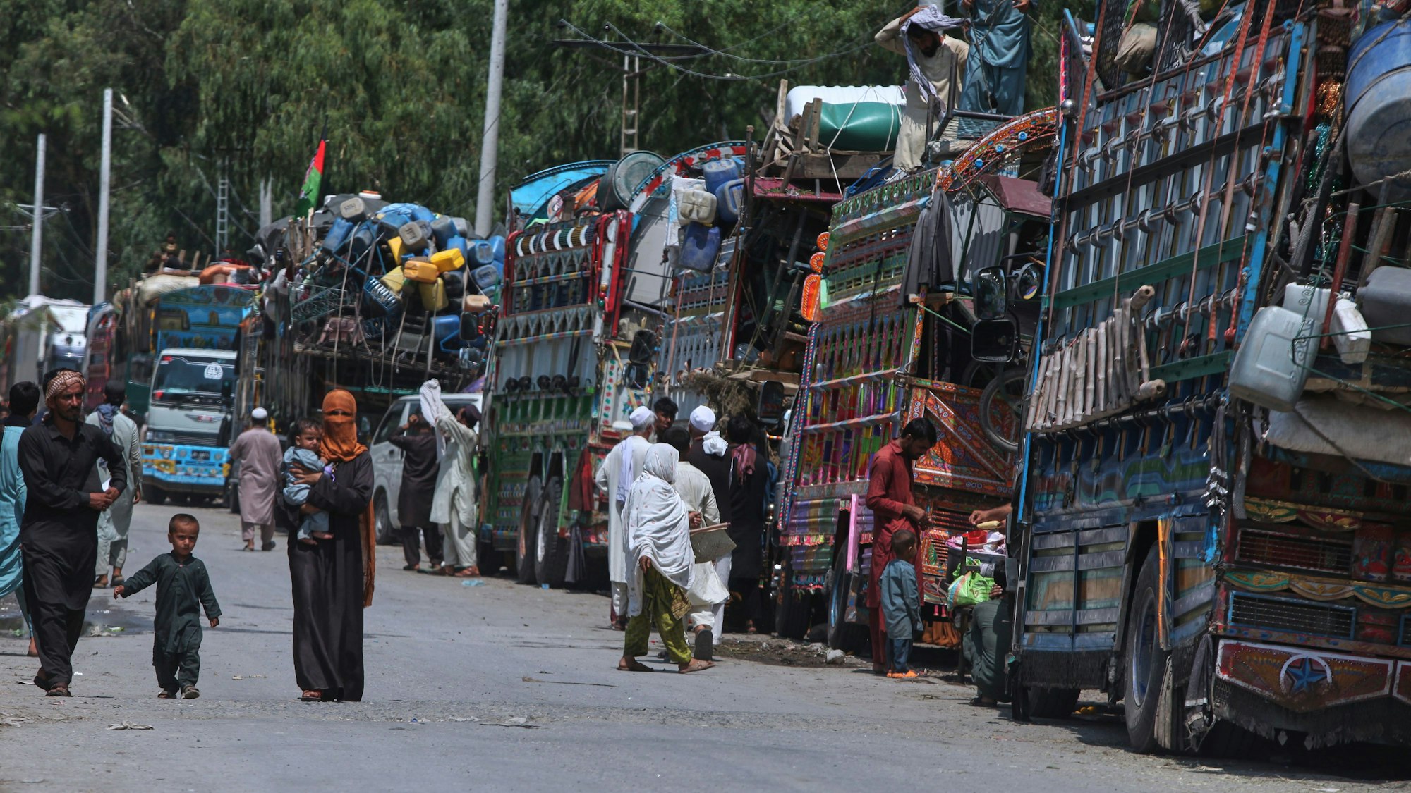 Manche wollen auch zurück: Afghanische Flüchtlingsfamilien, die auf dem Weg zurück in ihr Heimatland sind, versammeln sich in Pakistan neben Lastwagen, die mit ihren Habseligkeiten beladen sind.