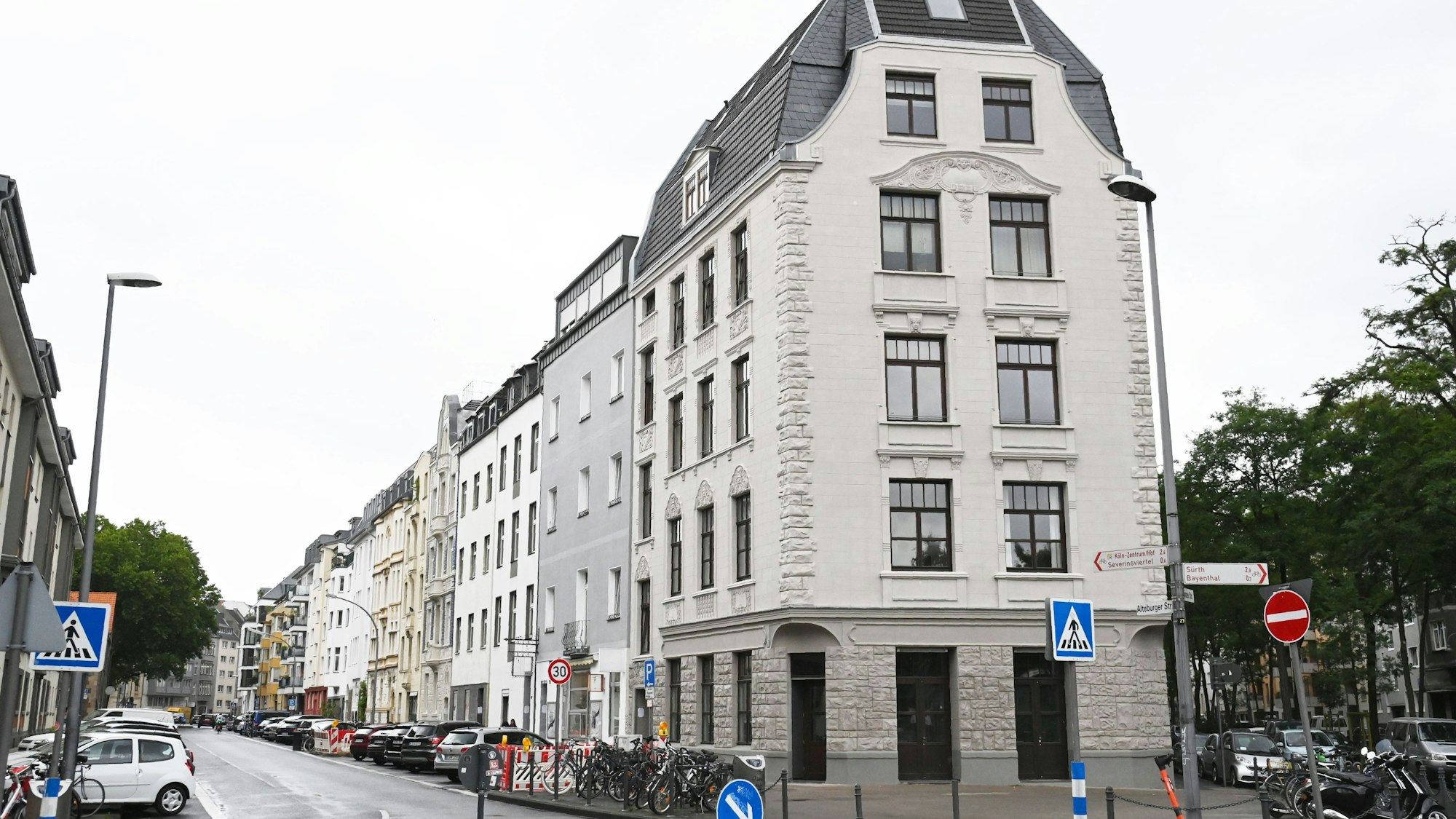 An einer Altbau-gesäumten Straße parken zahlreiche Autos.