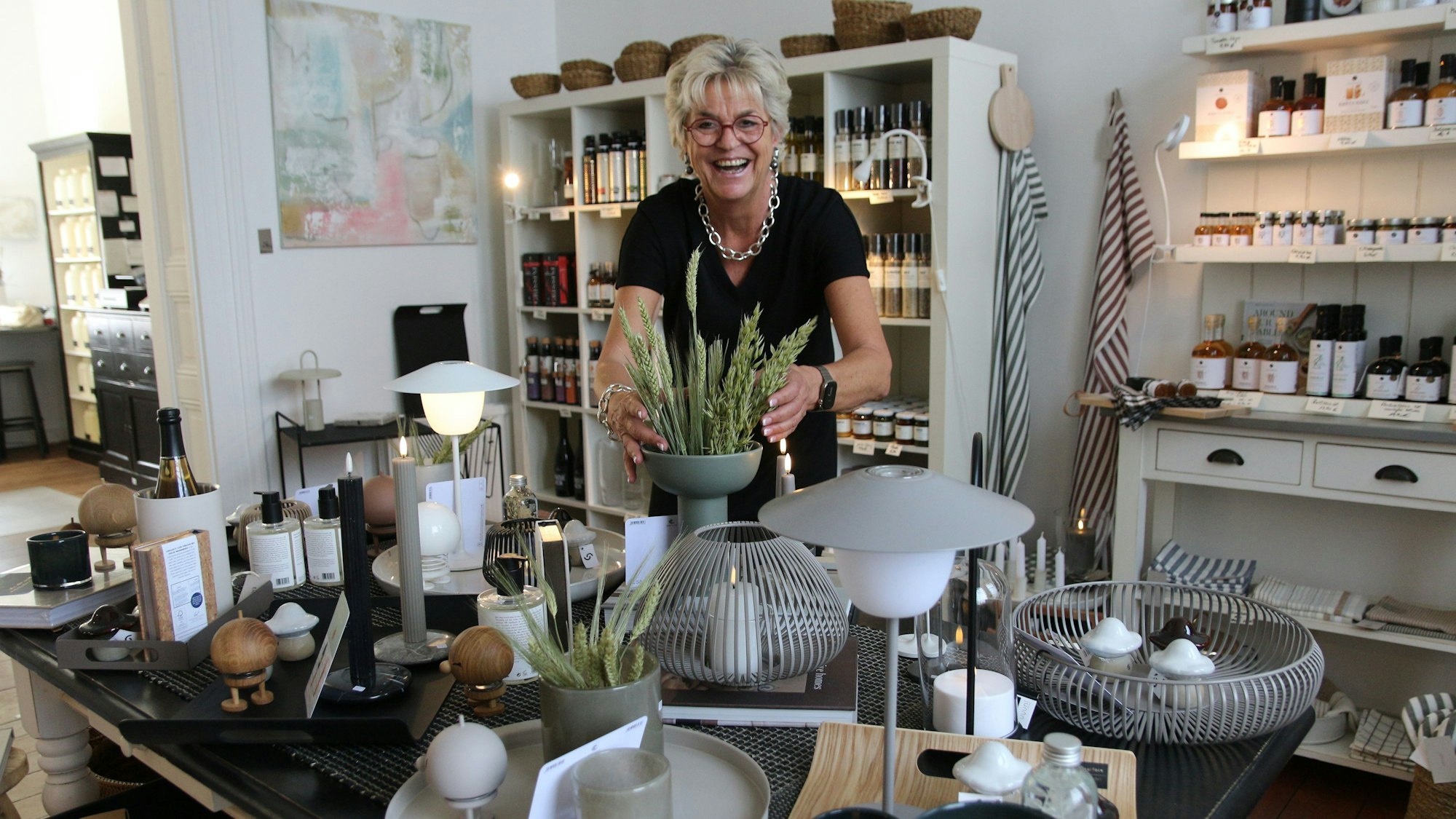 Auf dem Bild ist die Ladeninhaberin in ihrem Geschäft zu sehen.