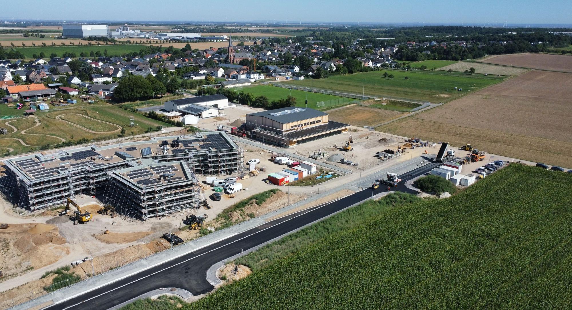 Die Drohnenaufnahme zeigt die im Bau befindliche neue Grundschule in Firmenich und im Hintergrund die Orte Firmenich und Obergartzem.