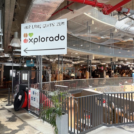 Ein Hinweisschild in einer Mall. „Hier lang geht's zum Explorado“ steht darauf.