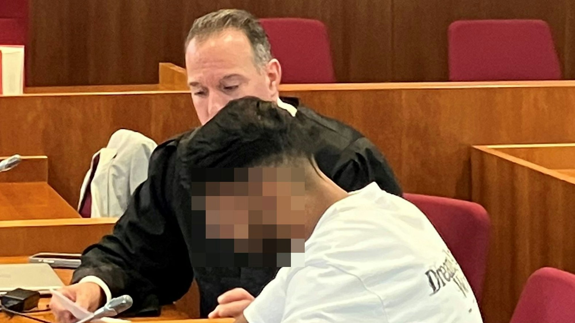 Das Bild zeigt den Angeklagten und seinen Verteidiger, sie sitzen nebeneinander im Gerichtssaal.