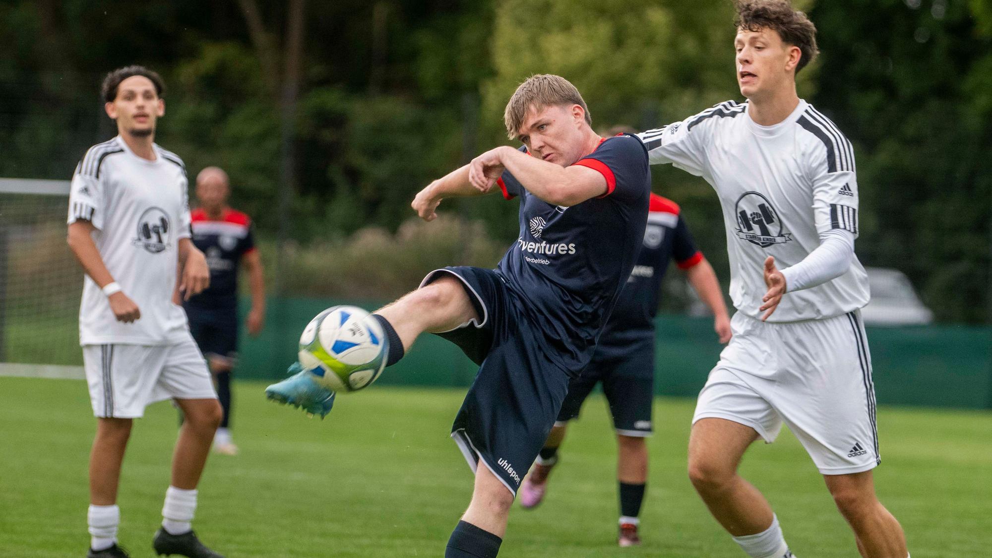 Ein Fußballer beim Torschuss, der Gegenspieler, der sich von hinten nähert, kommt zu spät.