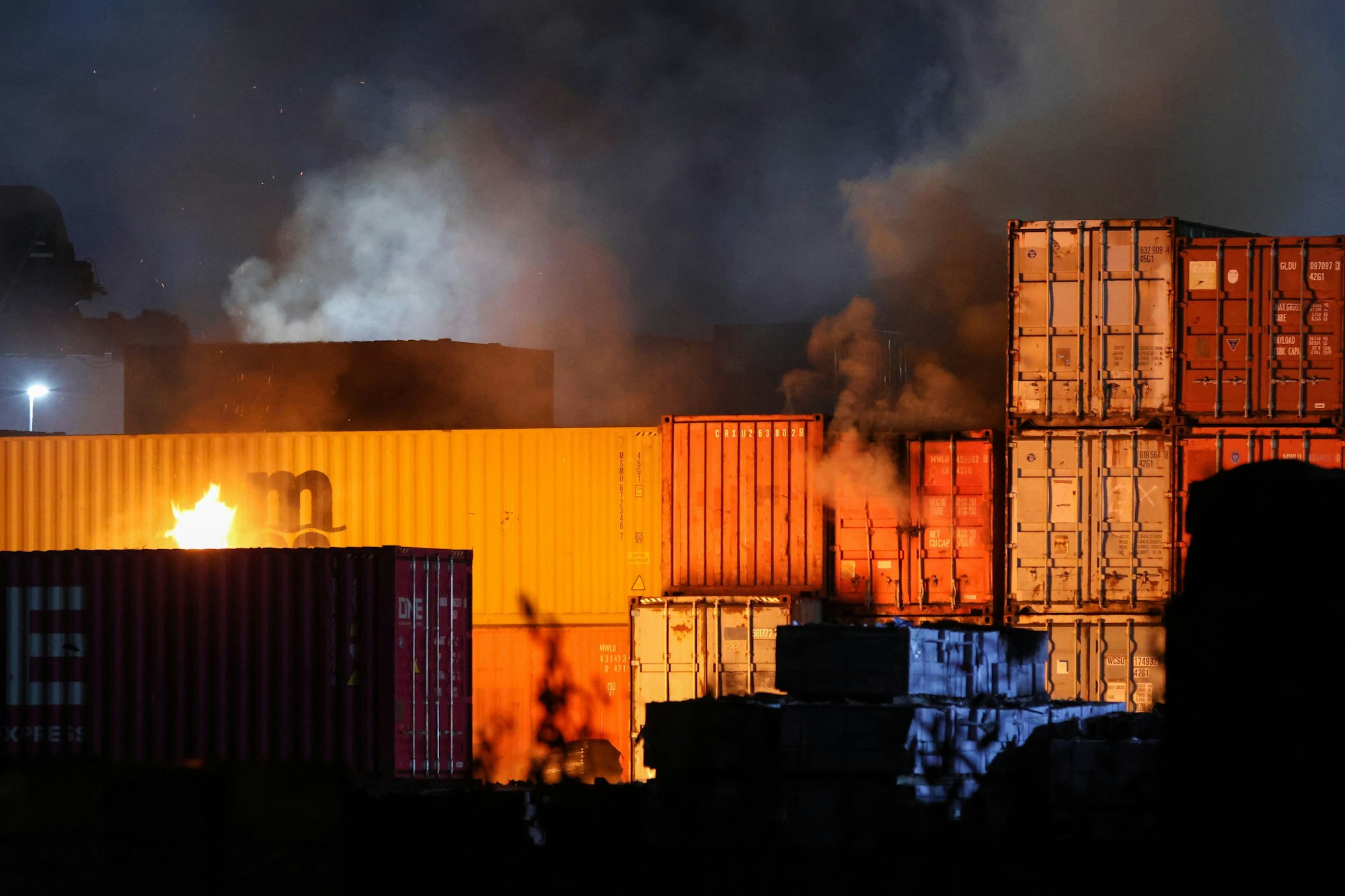 25.08.2025, Hamburg: Feuerschein ist bei einem Brand in einem Industriegebiet im Hamburger Hafen zu sehen. Nachdem in einer Lagerhalle in einem Hamburger Gewerbegebiet ein Feuer ausbrach kam es zu mehreren Explosionen. (zu dpa: «Großbrand im Hamburger Hafen - Löscharbeiten dauern an») Foto: Bodo Marks/dpa +++ dpa-Bildfunk +++