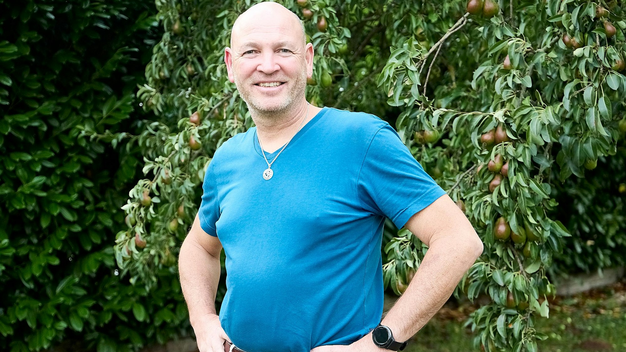 Dirk Nagelschmidt steht in einem blauen T-Shirt vor einem Baum.