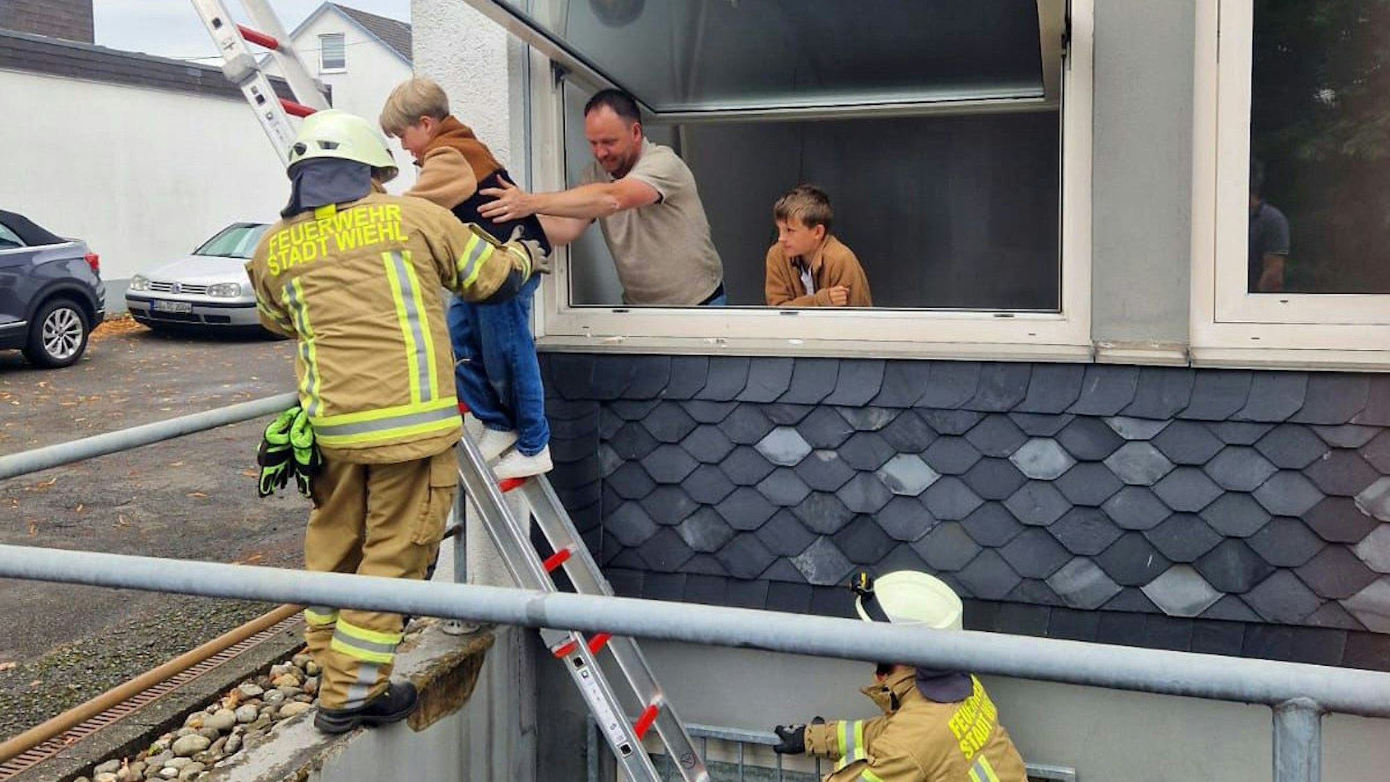 Ein Mann hilft einem Kind beim Abstieg über eine Feuerwehrleiter.