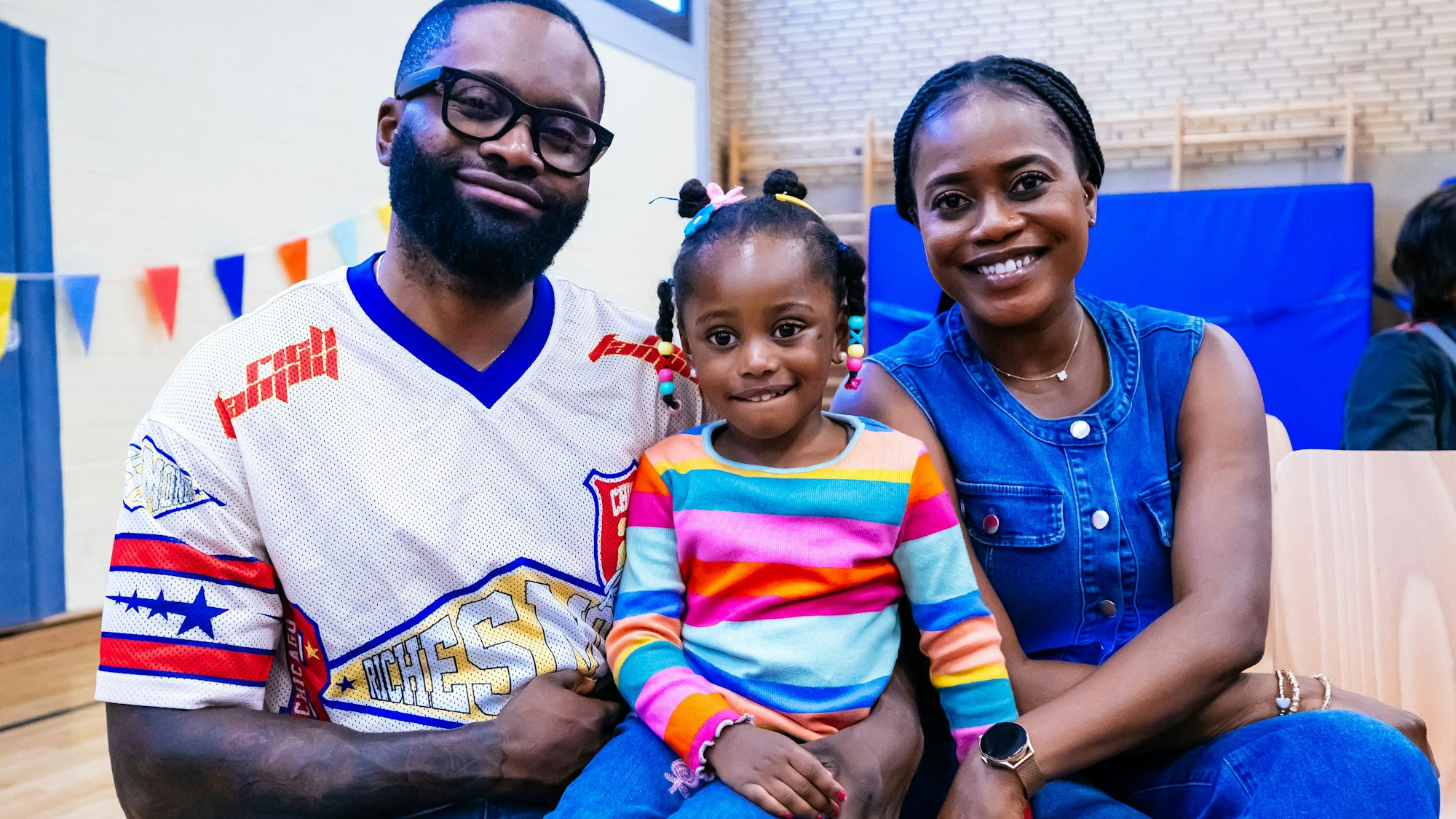 Eine Familie mit einem kleinen Mädchen lächelt in die Kamera.