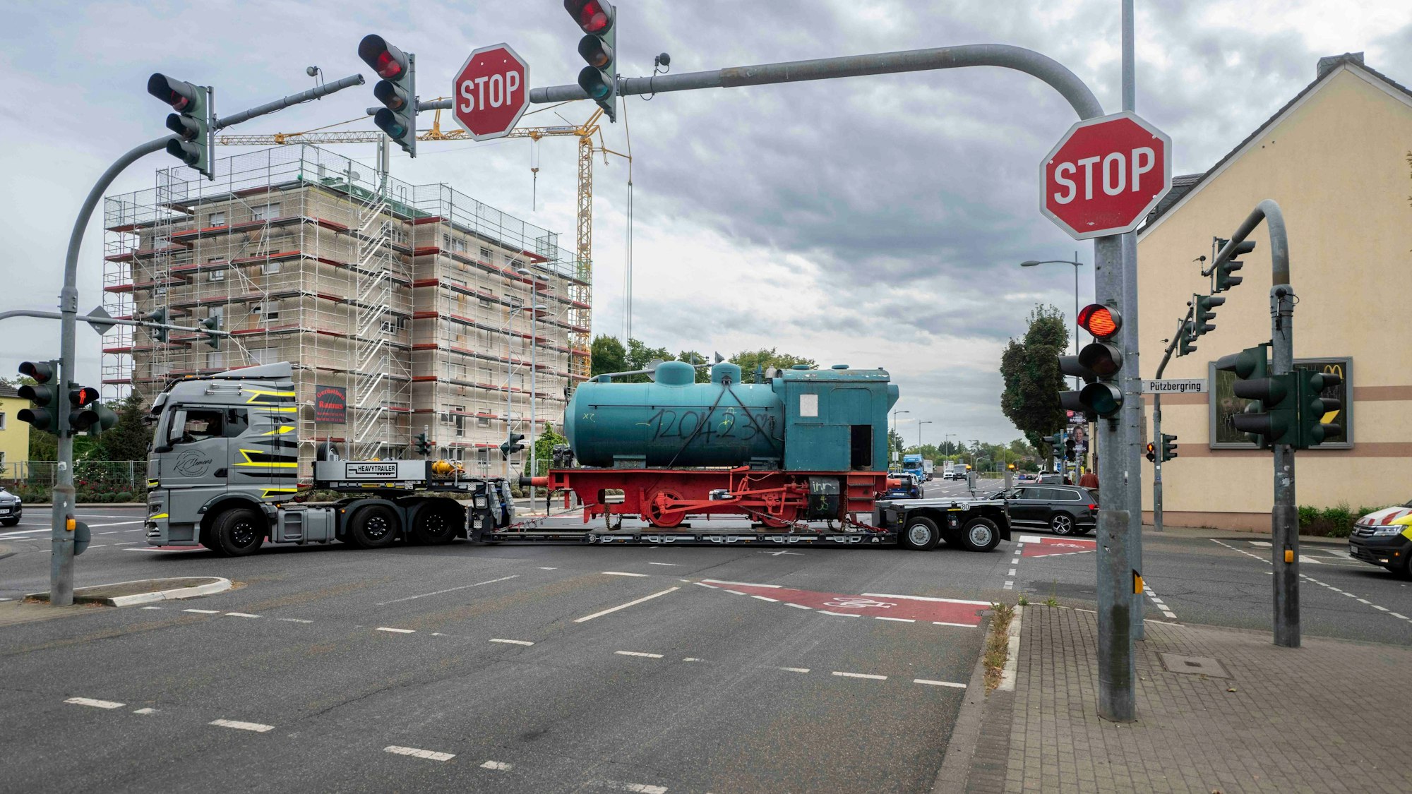 Das Bild zeigt den Moment, in dem die Lok auf dem Tieflader vom Pützbergring auf die Kölner Straße abbiegt.