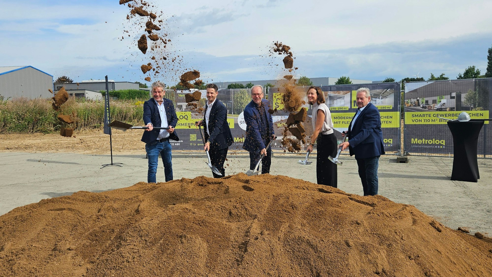 Zu sehen sind mehrere Personen mit Spaten an einem Erdhaufen.