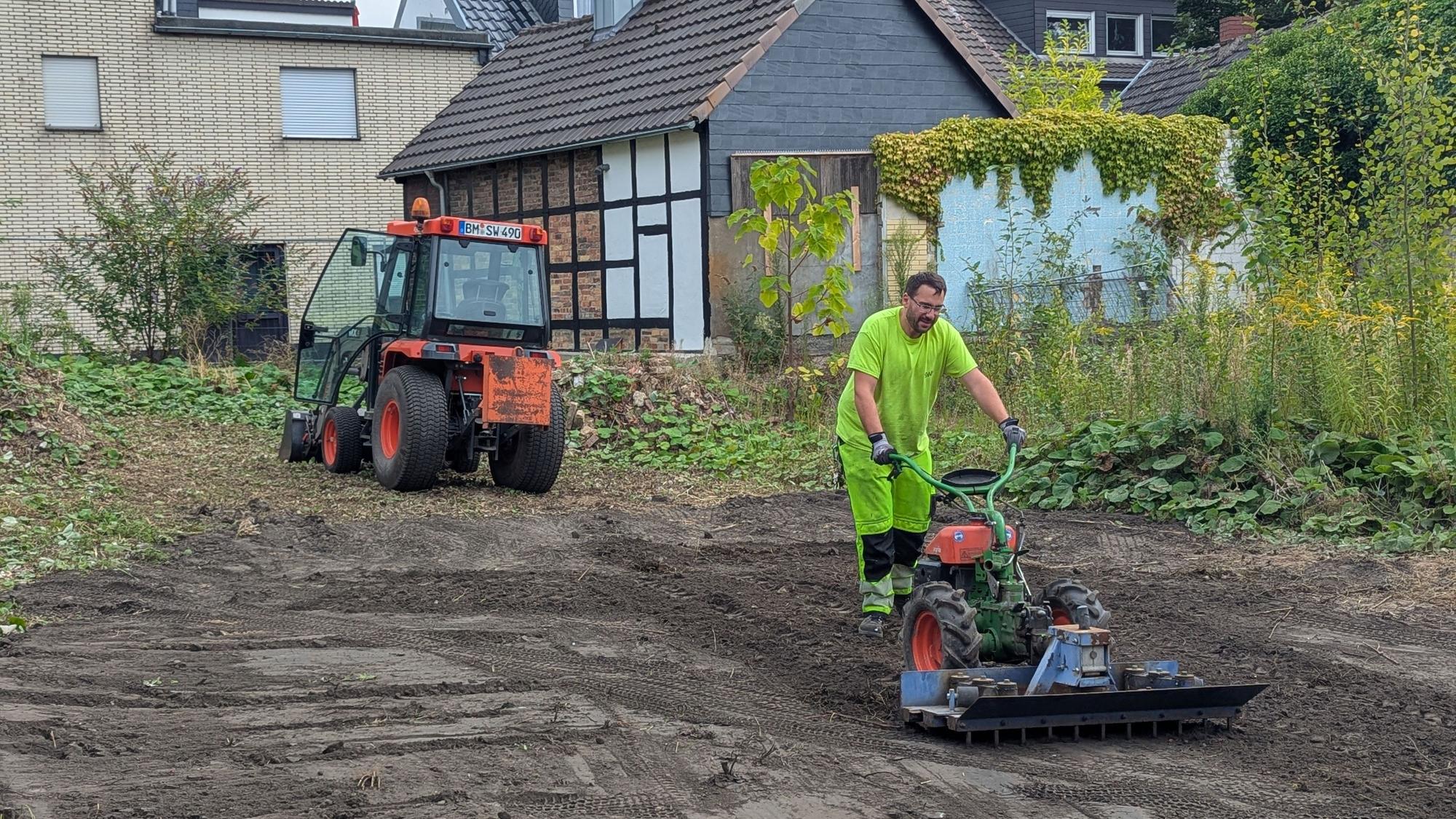 Das Foto zeigt einen Mitarbeiter der Stadtwerke beim Bearbeiten des Bodens, im Hintergrund ein Bagger.
