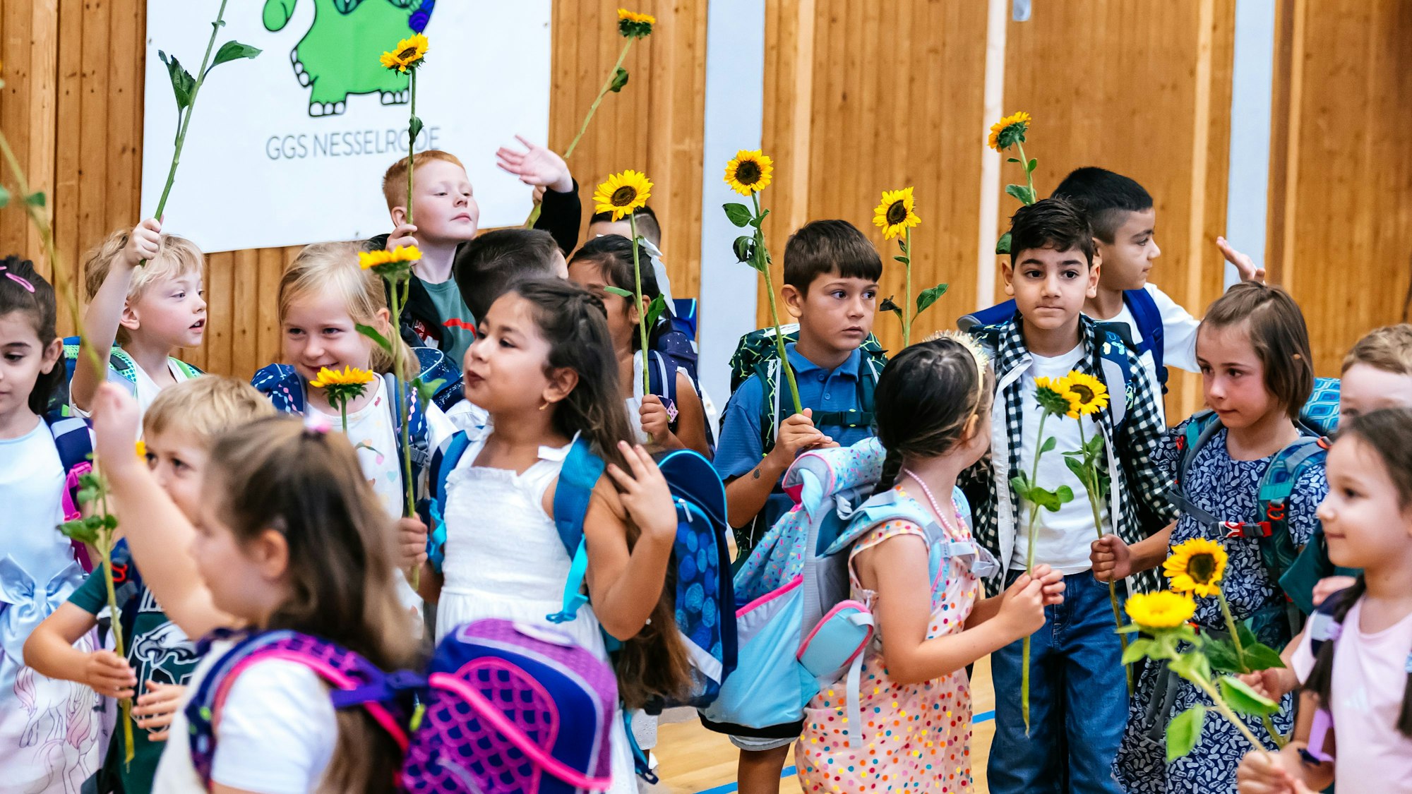 Kinder mit unterschiedlichen Gesichtsausdrücken, Schulranzen und Sonnenblumen.