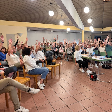 Teilnehmer einer Bürgerversammlung stimmen per Handzeichen ab.