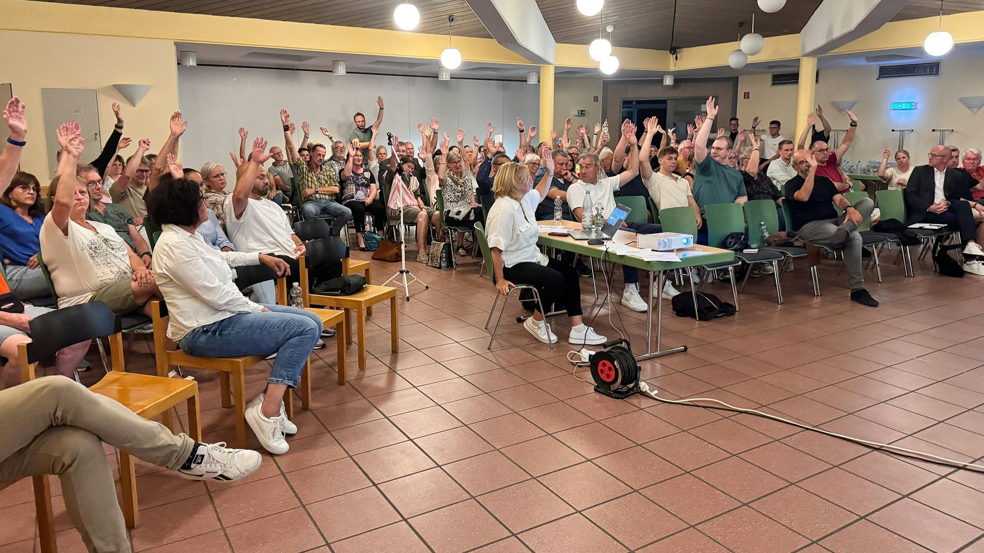 Teilnehmer einer Bürgerversammlung stimmen per Handzeichen ab.