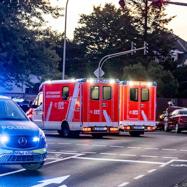Im Vordergrund des Symbolbildes stehen Polizeiautos an einer Kreuzung, im Hintergrund Rettungswagen.