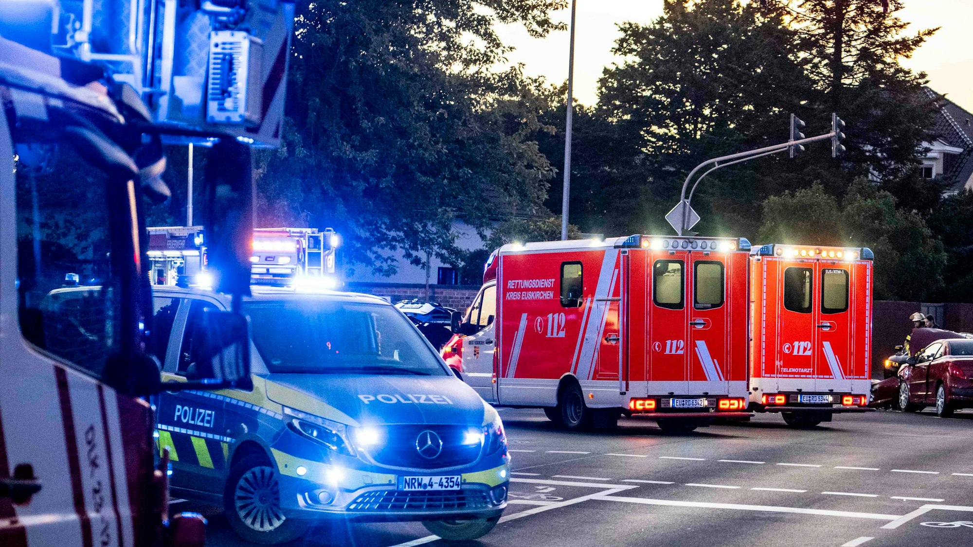 Im Vordergrund des Symbolbildes stehen Polizeiautos an einer Kreuzung, im Hintergrund Rettungswagen.
