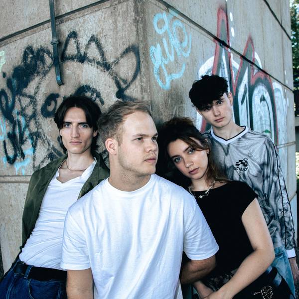 Vier junge Leute vor einer Graffiti-Wand.