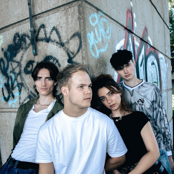 Vier junge Leute vor einer Graffiti-Wand.