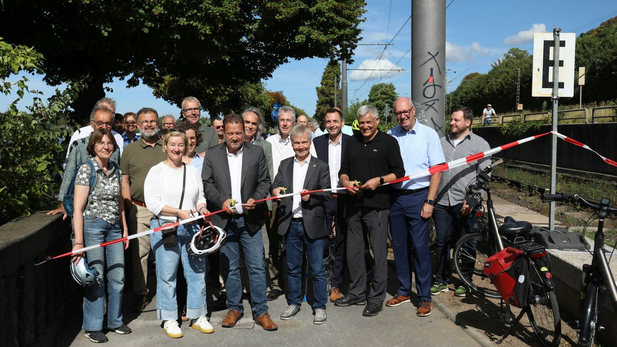 Eine große Gruppe Menschen hinter einem rot-weißen Absperrband.