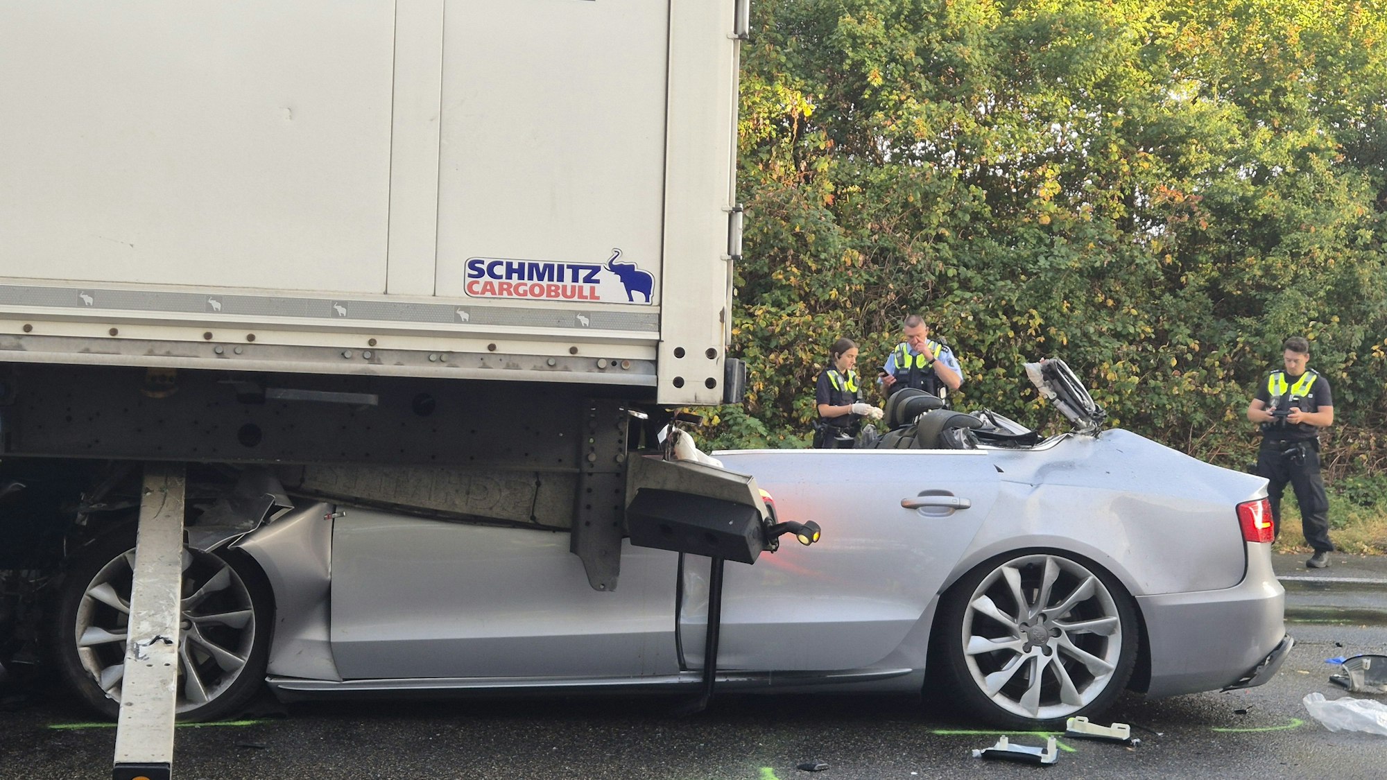 Ein Pkw steht nach einem tödlichen Unfall unter einem Lkw. Foto: Sascha Thelen/dpa