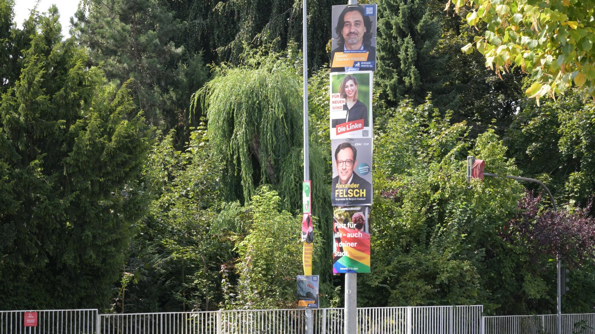Vier Wahlplakate hängen direkt übereinander an einem Mast.