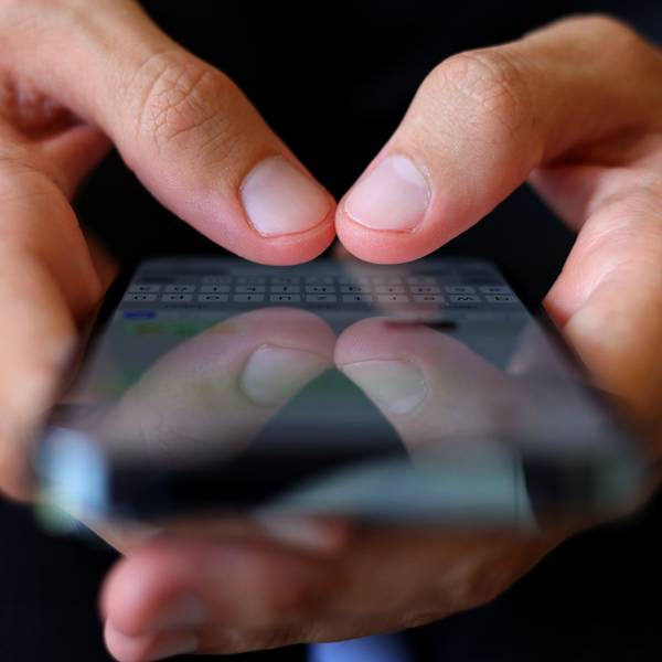 Ein junger Mann tippt auf einem Smartphone eine WhatsApp-Nachricht.