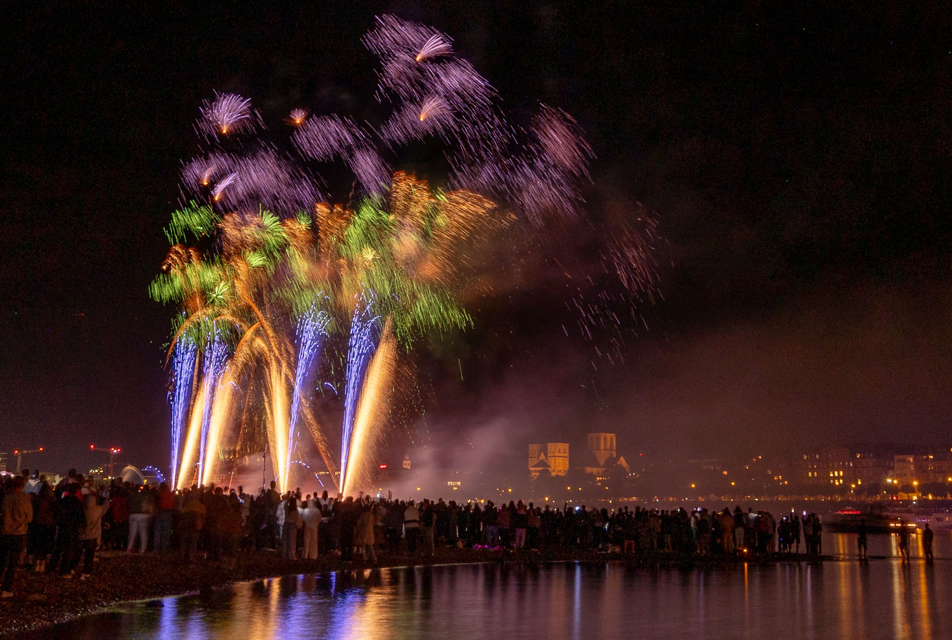Menschen besuchen im Kölner Rheinpark das größte musiksynchrone Feuerwerk Europas.